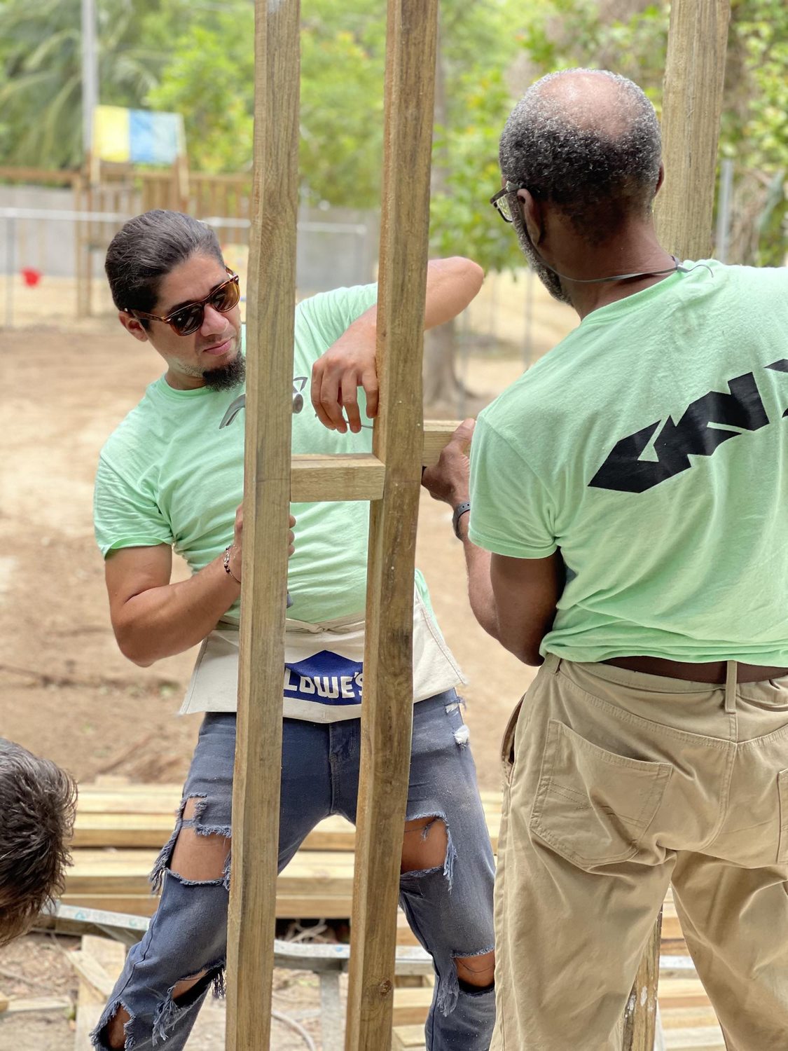 Two students nailing vertical lumber posts for the classroom wall frame on the bare concrete slab